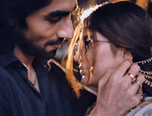 a man touching a woman 's ear with a gold ring