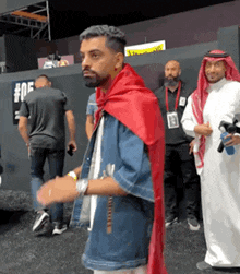 a man wearing a red cape is standing in front of a group of men .