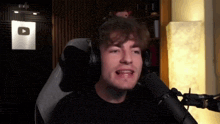a man wearing headphones is sitting in front of a youtube logo