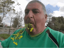 a man in a green shirt is eating flowers