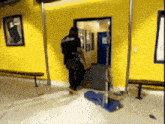 a man in a police uniform is standing in a room with a yellow wall and a blue door .