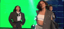 three women are dancing on a stage with a green screen in the background .