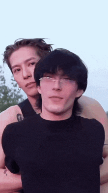 two young men are posing for a picture together . one of the men is wearing glasses .