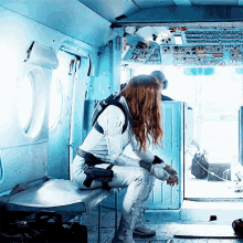 a woman in a white suit sits on a bench in a plane
