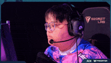a man wearing glasses and headphones is sitting in front of a screen that says secret lab ace predator