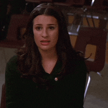 a woman in a green sweater is smiling and clapping