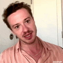 a man with a beard wearing a pink striped shirt and a silver chain around his neck