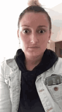 a woman wearing a white jacket and a black hoodie is making a funny face .