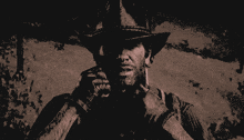 a man wearing a cowboy hat is covering his face with his hands