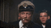 a man in a military uniform salutes with a cigarette in his mouth