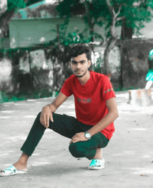 a young man wearing a red t-shirt with the word gucci on it is squatting down