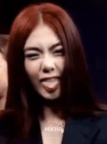 a woman with long red hair is sticking her tongue out .