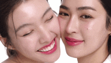 a woman with pink lipstick kisses another woman 's face