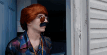 a man with a fake mustache and sunglasses looks out a window