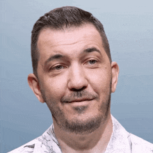 a man with a beard is wearing a white shirt with barbed wire on the collar