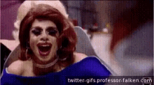 a woman in a wig is laughing with her mouth wide open while sitting in a chair .