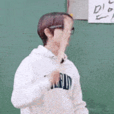 a man wearing glasses and a white hoodie is standing in front of a blackboard .