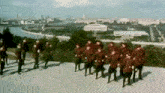 a large group of soldiers are marching in a line on top of a hill .