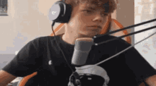 a man wearing headphones and a microphone is sitting in front of a microphone .