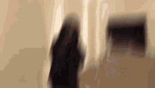 a blurry picture of a woman standing in front of a wall .