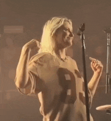 a woman is singing into a microphone while wearing a number 93 jersey .