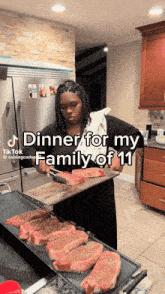 a woman is holding a tray of steaks and says " dinner for my family of 11 " on the bottom