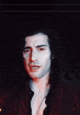 a man with long curly hair and red eyes is wearing a red jacket