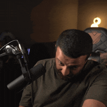 a man with a beard is smiling in front of a microphone while sitting in a chair