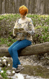 a woman reading a book while sitting on a log