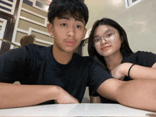 a boy and a girl are posing for a picture while sitting at a table