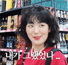 a woman in a red shirt is making a funny face in front of a shelf of alcohol