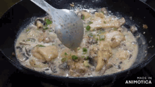 a pan of food is being stirred with a spoon and the words made in animotica are visible