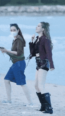 a woman wearing a mask is walking along the beach