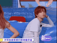 a girl with red hair is sitting in front of a sign that says ' iqiyi ' on it