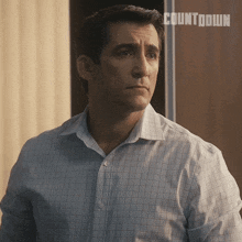 a man in a plaid shirt is standing in front of a wall that says countdown