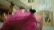 a woman in a pink dress is sitting on a couch in a room .
