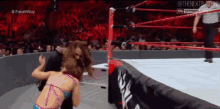 a woman in a bikini is wrestling another woman in a ring .