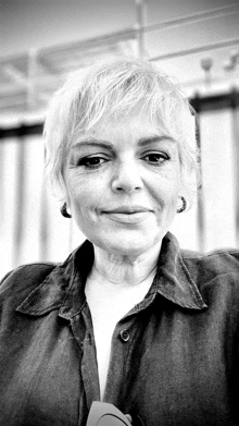 a black and white photo of a woman wearing a denim shirt and earrings