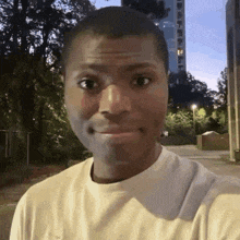 a man in a white shirt is making a funny face while standing in front of a tall building .