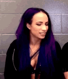 a woman with purple hair is standing in front of a wall .