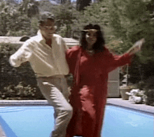 a man and a woman are dancing in front of a pool .