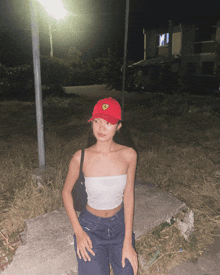 a woman wearing a red ferrari hat and a white crop top