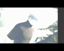 a man in a black turtleneck stands in front of trees