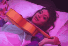 a woman is laying in bed holding a violin in her hands .