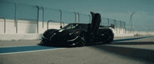 a black sports car with its doors open is parked on a track