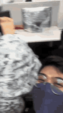 a person wearing a blue mask and glasses is sitting in front of a desk .