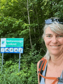 a woman smiles in front of a sign that says nottawasaga lookout