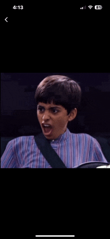 a young boy is making a funny face on a phone screen .