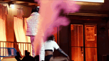 a woman sitting in front of a pink smoke filled room
