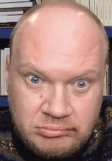 a man with a beard and a bald head is making a funny face .